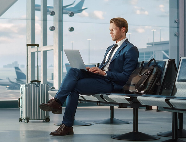 Dizüstü bilgisayar ile bir havaalanında oturan bir adam