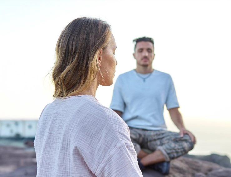 Yoga yapan bir kaya üzerinde oturan bir erkek ve bir kadın